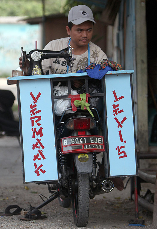 Уличен шивач чака клиенти на улица в Депок, Индонезия.