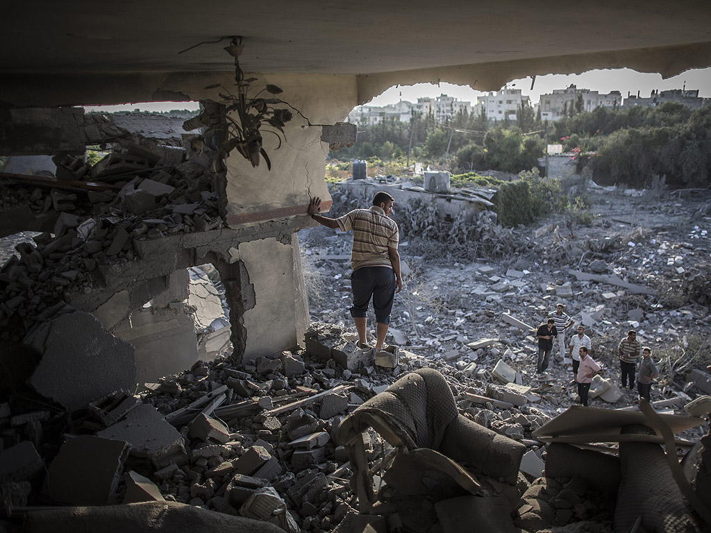 Палестинец стои в остатъците от жилището си след бомбардировка от израелската армия на 8 август