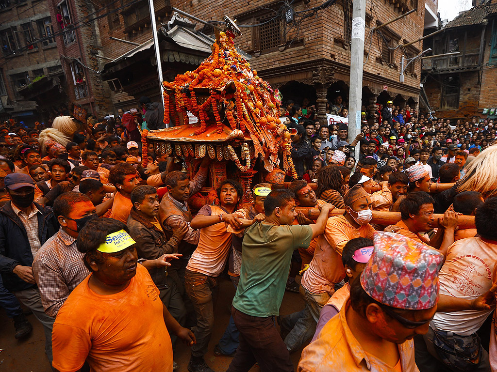 Непалци пеят и танцуват на традиционна музика с цветен прах по лицата си по време на Bisket Jatra фестивал в покрайнините на Катманду, Непал. Фестивалът Bisket маркира непалската Нова Година 2072 и се празнува за мир и хармония в страната