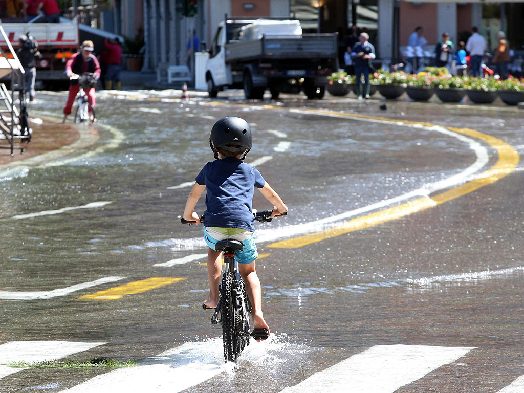 Дете кара велосипед по улица залята от придошлите води на езерото Комо в квартал Кавур в Комо, Италия