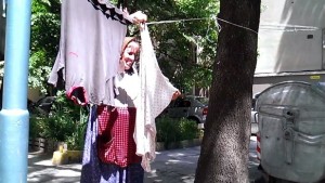 Баба простира прането си между стълб и дърво в центъра
