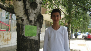 Момче от Червен брег слага табели върху дърветата за да