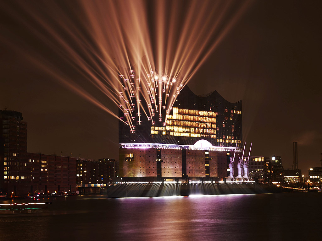 Светлини осветяват Филхармонията на Елба по време на церемония по откриването в Хамбург, Германия. Сред забележителностите в сградата е единственият дъговиден ескалатор в света. Залата с 2100 места е на върха, за да има по-добра акустика и е с разгъната застроена площ 4000 кв.м. . Уникалният комплекс, в който има хотел, апартаменти, ресторант и търговски център е проектиран от швейцарското архитектурно бюро "Херцог & дьо Мьорони" е строен 10 години. Цената му достигна близо 800 милиона евро. Зданието има формата на нос на кораб и се намира на входа на пристанищния немски град.