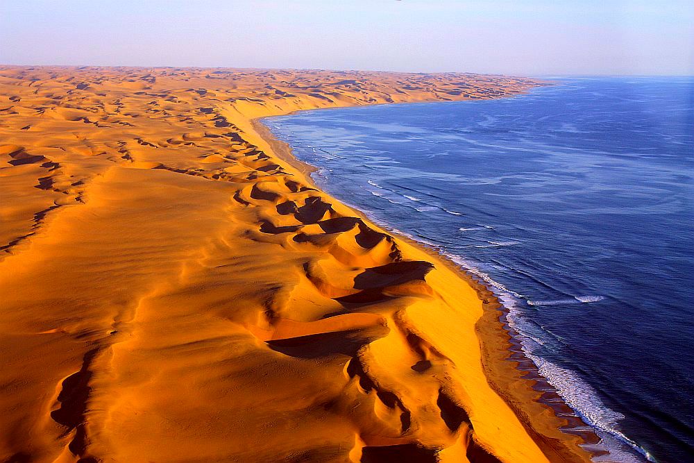 <strong>Където пустинята Намиб среща океана</strong><br>
<br>
Намиб е пустиня, разположена в дълга тясна ивица по Атлантическото крайбрежие на Южна Африка. Образувана от Бенгелското Атлантическо течение. Само тук можете да видите тази зрелищна гледка, където кехлибарено-жълтите дюни граничат с ръба на тъмносиния океан. Студените води се плискат срещу пясъците и създават един сюрреалистичен пейзаж, който се простира на стотици километри.