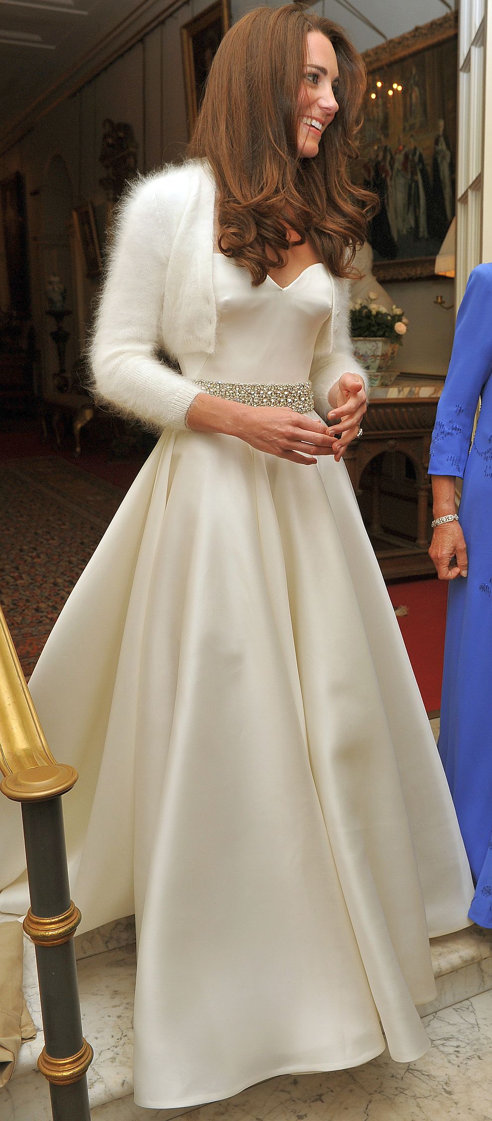  На приема в Бъкингамския замък булката, към този момент като херцогинята на Кембридж Катрин, се появи в изискана рокля от бял сатен с внимателен колан, сътворена от Сара Бъртън 
