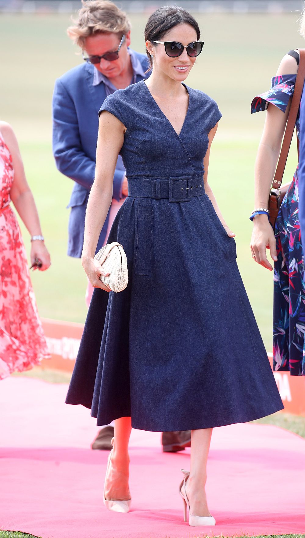 Херцогинята на Кеймбридж Меган в тъмносиня рокля на венецуелската дизайнерка Каролина Ерера по време на благотворителна игра на поло в Уиндзор, в която Хари взе участие.<br>
 