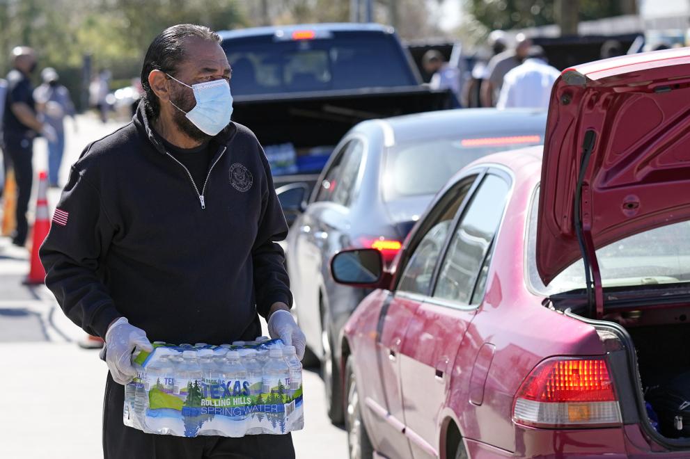 Тексасец слага в багажника на колата си бутилки питейна вода в снабдителен пункт в Хюстън