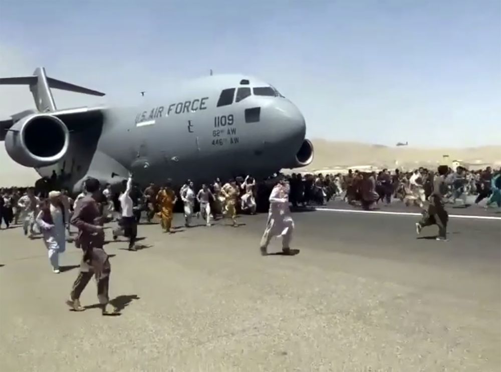 Стотици хора тичат покрай самолет на САЩ, докато той се движи по пистата на международното летище в Кабул