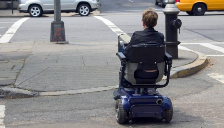 електрическа инвалидна количка - Автомобил помете мъж в инвалидна количка на пешеходна пътека