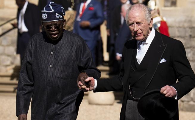 Президентът а Нигерия Бола Ахмед Тинубу и крал Чарлз се държат за ръце