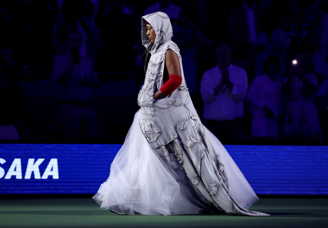 <p>Четирикратната шампионка от Големия шлем шокира феновете на US Open с роба от вестникарски заглавия и екип в стил Алън Айвърсън. Японката премина през труден мач срещу Захарова и обеща още модни изненади в следващия кръг.</p>
