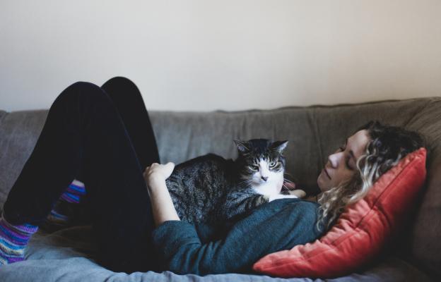 Жена лежи с котка върху нея