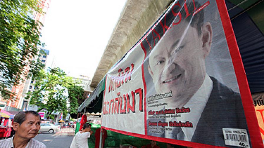 Мъж  минава покрай плакат  на бившия премиер Таксин Шинаватра в район на Банкок, окупиран от "червените ризи"