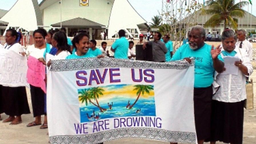 Жители на Кирибати настояват за решение на проблема им. На плаката пише: "Спасете ни, давим се"