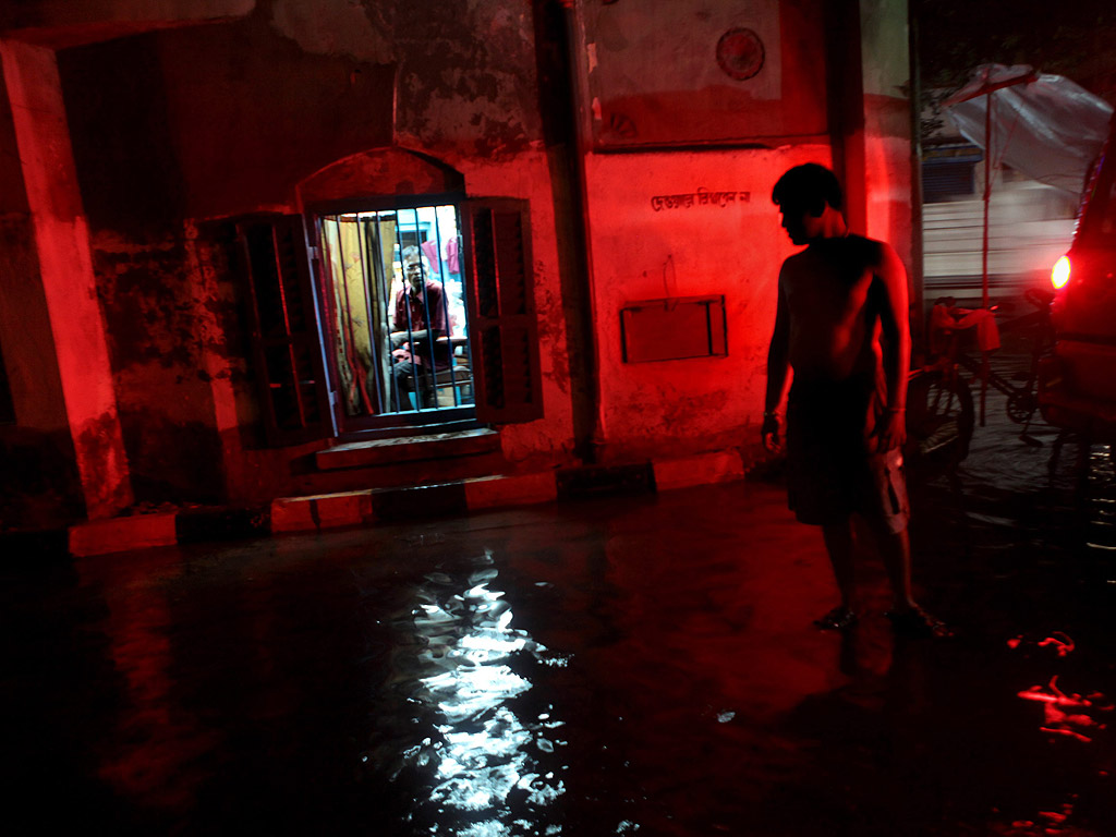 Индиец стои на наводнена улица след пороен дъжд в Колката, Индия, на 21 август.