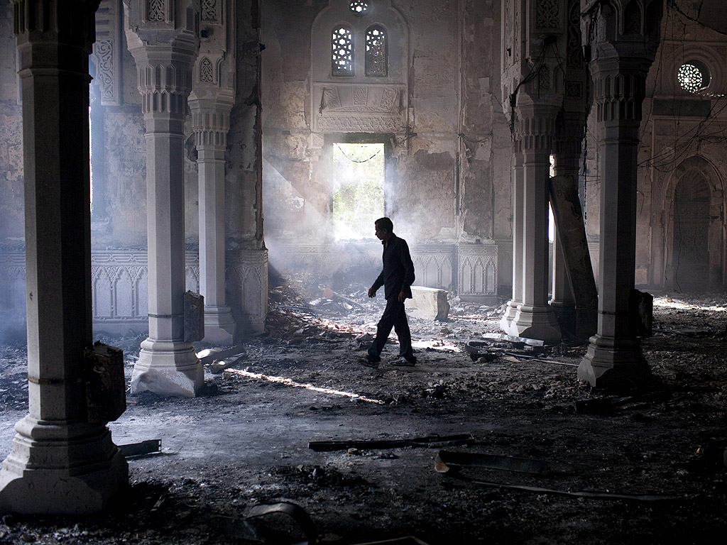 Човек, ходи в изгорялата Rabaa Adawiya джамия, на сутринта след разчистването на седящата стачка, която се проведе в и около джамията, в Кайро, Египет, 15 Август 2013. Най-малко 421 души са били убити в Египет на 14 август в стълкновение с полицията и два  основни протестни лагера в Кайро, създадени от поддръжници на сваления президент Мохамед Морси, заяви Министерството на здравеопазването